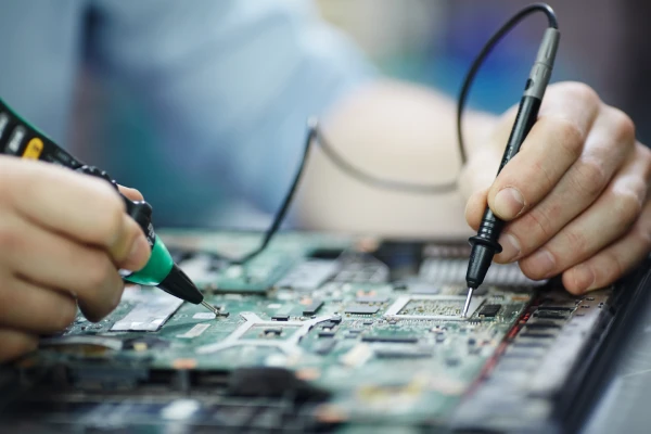 unas manos midiendo componentes en una placa de notebook